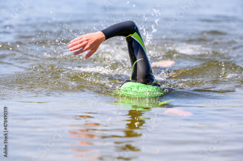 Swimmer swimming outdoor in nature with a green swimming cap and orange buoy
