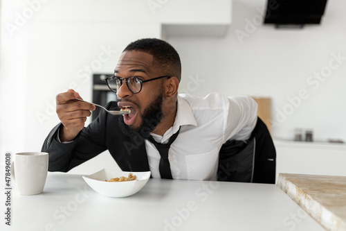 Black man rushing to work eating cereal at home