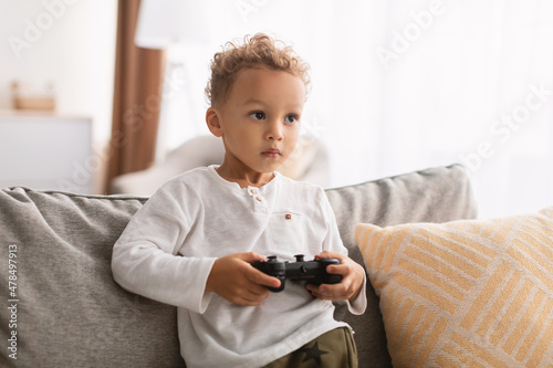 African American Boy Playing Videogame Sitting On Sofa Indoor