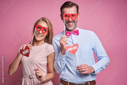 Cuadro en lienzo Caucasian couple at Valentine's Day posing on pink background with photo booth a