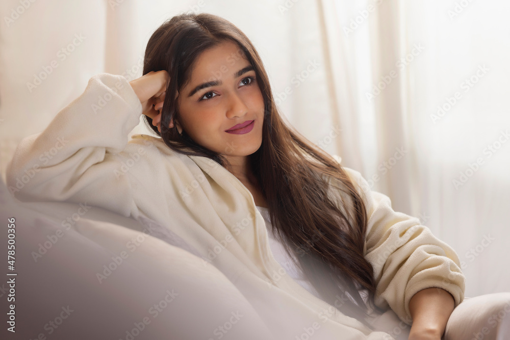 Girl looking away while sitting on sofa at home Girl looking away while sitting on sofa at home