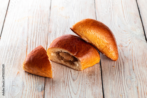 Freshly baked tasty bun on a white wooden table. Tasty baked goods straight from the bakery. White background.