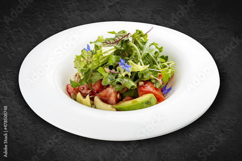 Salad with avocado and pine nuts. Isolated on a black background.