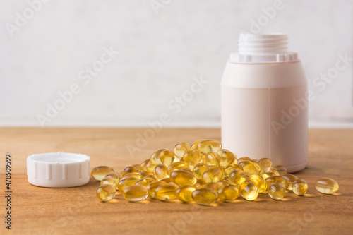 oil capsules, omega 3 and vitamin supplement on a wooden table top with the bottle, healthy lifestyle concept, with copy space for text, template