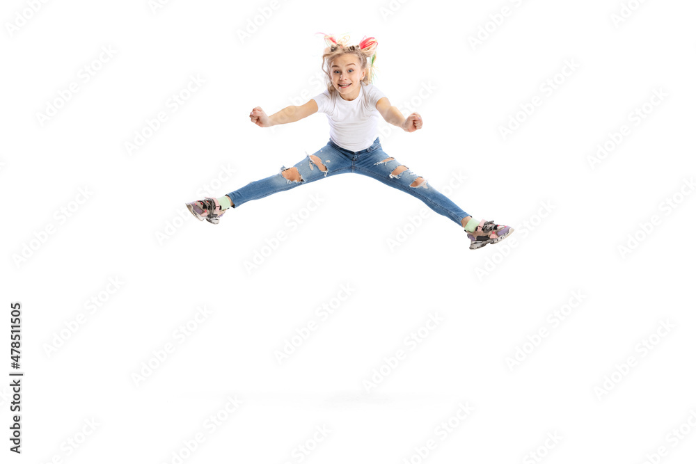 Emotional beautiful little girl, kid in casual clothes jumping, having fun isolated on white studio background.