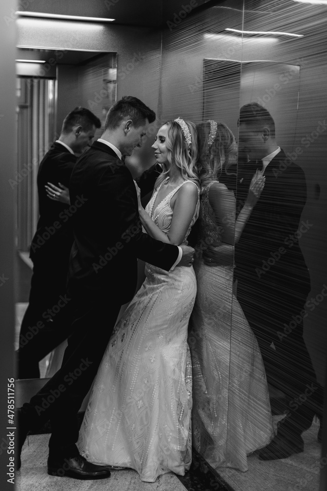 Black white vertical photo of young couple bride and groom kissing in elevator, tenderness, wedding. Sensual hugs, first Wedding night. Husband and wife.