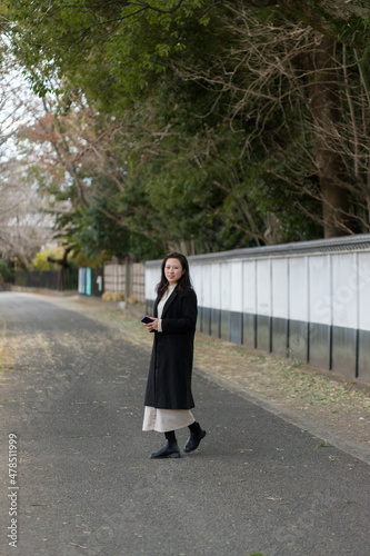 冬の岡山の後楽園の敷地で散歩している若い女性