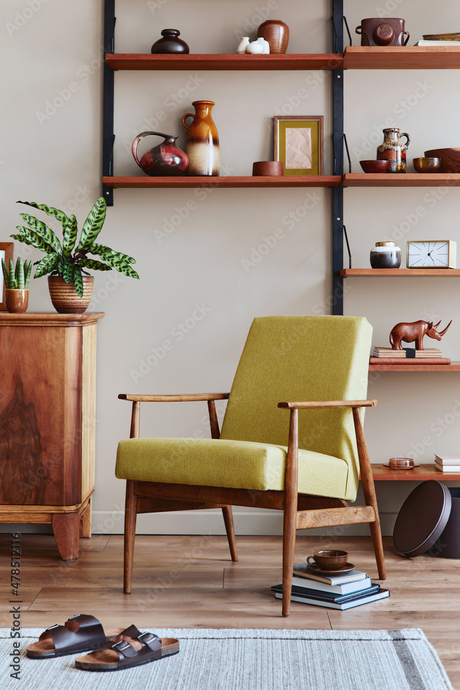 Obraz premium Stylish composition of retro living room interior with design armchair, wooden bookcase, picture frames, plant, carpet, slippers, decoration and elegant accessories in home decor. Template.