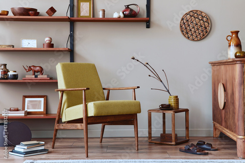 Stylish composition of retro living room interior with design armchair, wooden bookcase, coffee table, picture frames, plant, carpet, decoration and elegant accessories in home decor. Template. © FollowTheFlow