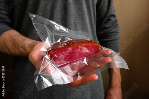 A man is holding a vacuum-packed red fish. Beautiful tuna