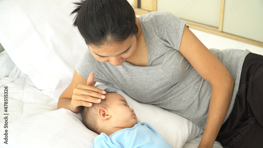 young mother Singing lullaby touching baby sleeping with love and tenderness.