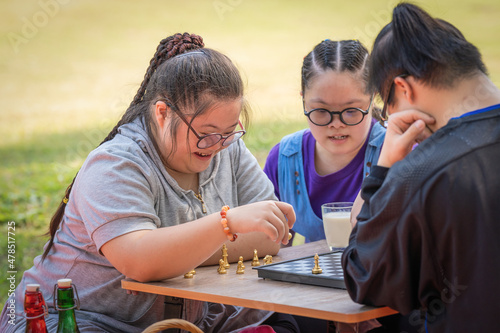 Foto group of friends with down syndrome playng chess board together