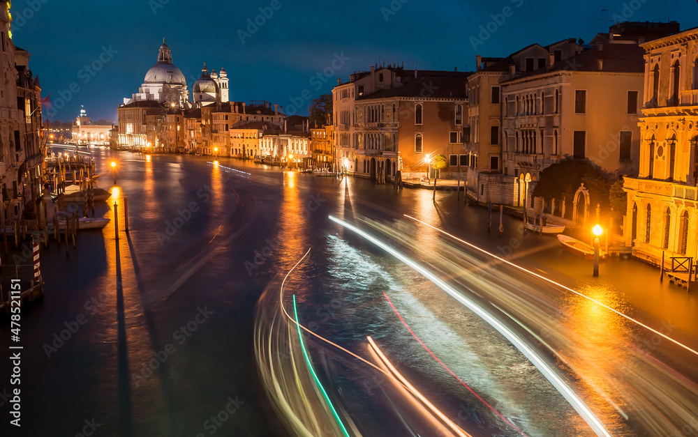 Beautiful night city Venice with water canals, riverboats in motion blurs and historical mansions