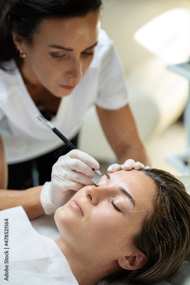 Woman during professional eyebrow mapping procedure Woman during professional eyebrow mapping procedure
