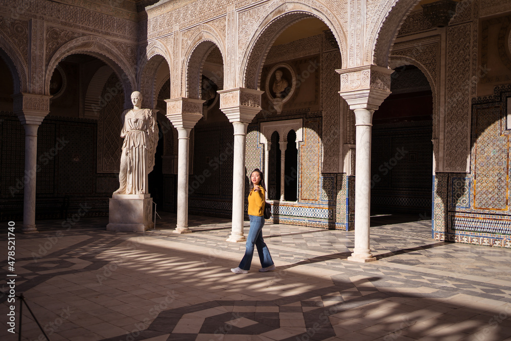 Naklejka premium young attractive Asian woman walking by monument in Seville