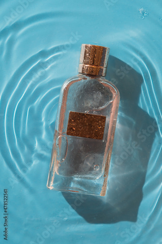 perfume bottle on a blue background in water, copy space