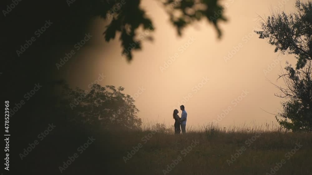 Young man and woman hugging and showing love feelings on beautiful summer evening. Happy couple enjoying romantic moment or date at nature scene. Concept of loving relationship or romance. Slow motion Young man and woman hugging and showing love feelings on beautiful summer evening. Happy couple enjoying romantic moment or date at nature scene. Concept of loving relationship or romance. Slow motion