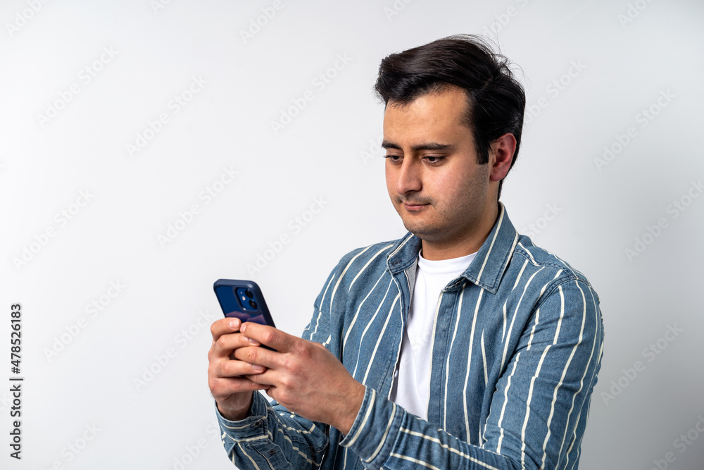 Close up photo of a brown skinned young adult model, texting with friends on social media with smartphone on isolated white background. Close up photo of a brown skinned young adult model, texting with friends on social media with smartphone on isolated white background.