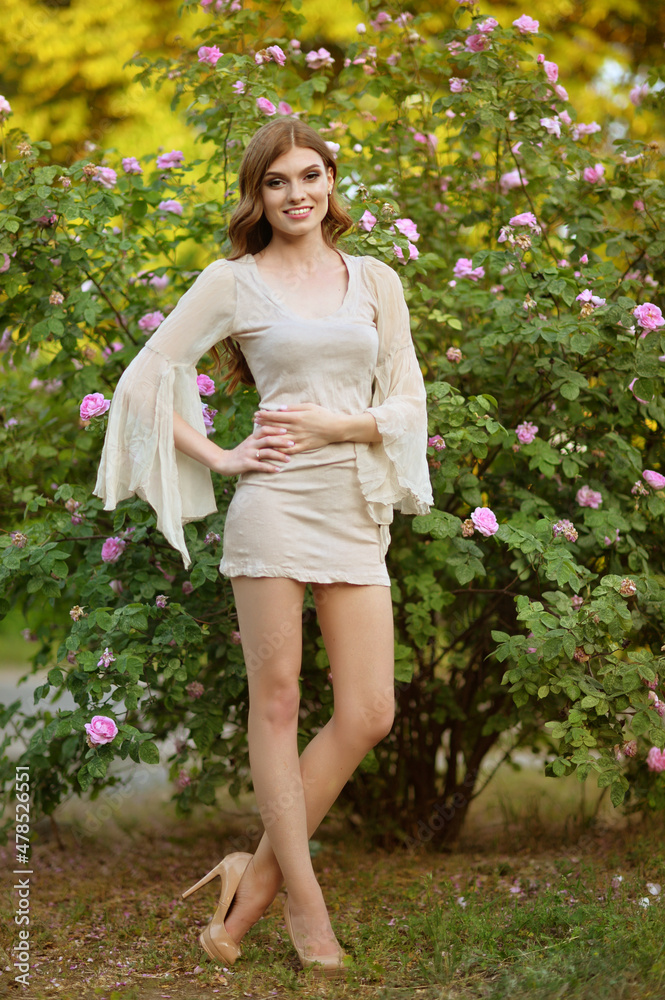 Portrait of beautiful young woman posing by rose bush Portrait of beautiful young woman posing by rose bush