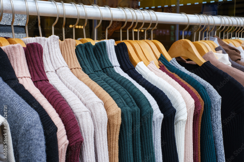 Obraz premium Knitted clothes hanging on wooden hangers close-up side view.
