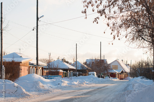 Several residential buildings on the snowy street of the village in Russia