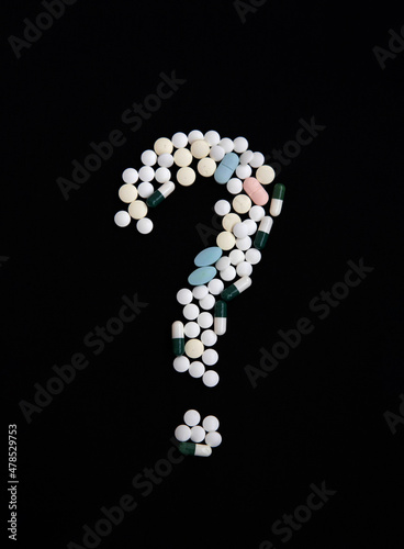 A question mark made of pills on a black background. The concept of vaccination and health protection