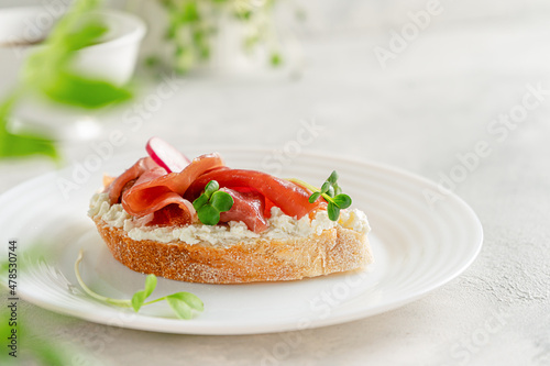 Prosciutto sandwich with cream cheese and micro greens on white plate. Italian cuisine. Copy space