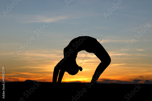Fototapeta Naklejka Na Ścianę i Meble -  Silhouette of female doing yoga in the mountains at sunrise sky background