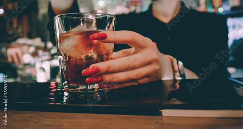 Closeup shot of bartender hand making negroni cocktail. Negroni classic cocktail and gin short drink with sweet vermouth, red bitter liqueur and dried orange garnish. photo