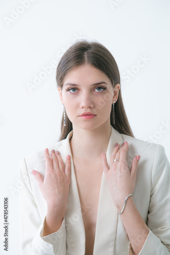 Trending silver jewelry set on a beautiful young girl in a white fashionable jacket  with long dark hair. Beauty and fashion 
