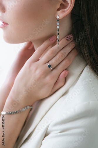 Trending silver jewelry set on a beautiful young girl in a white fashionable jacket with long dark hair. Beauty and fashion 