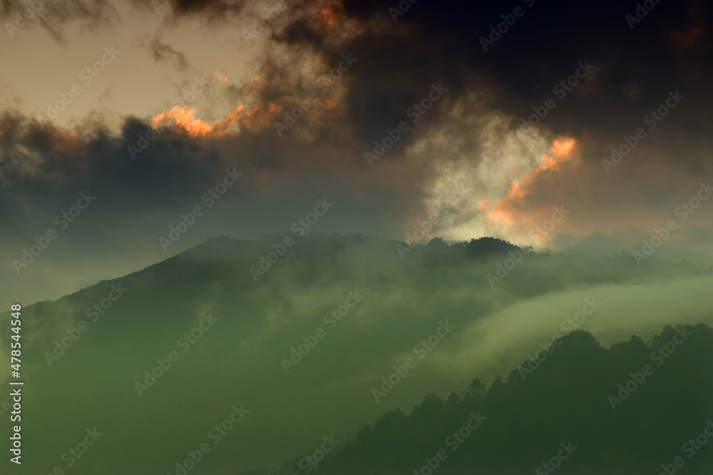 Light coming through window of clouds from setting sun, over Himalayan Mountain peaks. Dramatic cloud formation with sunset colours over Indian Mountain peaks.