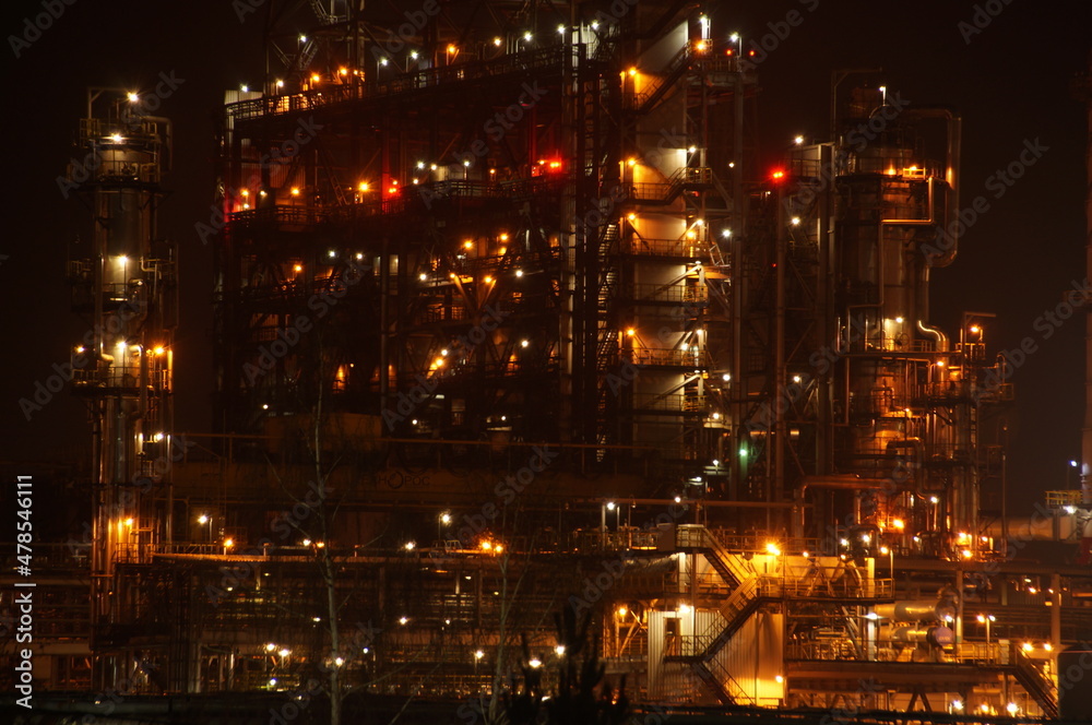 Technological installation at an oil refinery. Lighting of factory equipment at night. The light from the lamps at the enterprise. 