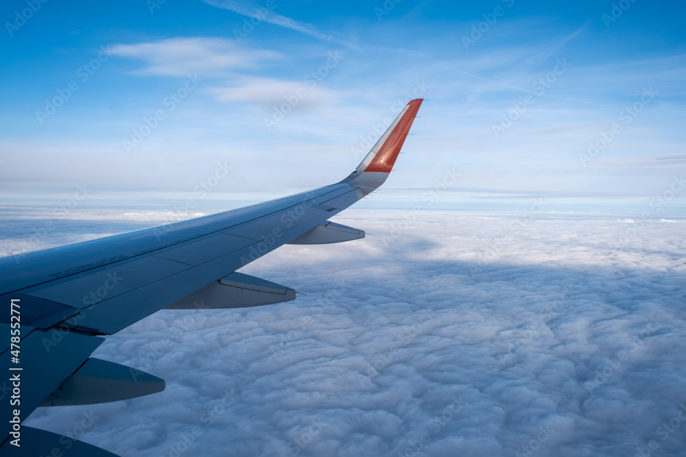 Classic image through aircraft window onto wing. Flight view over clouds