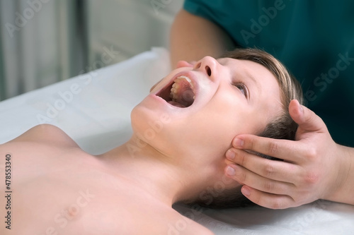 Wallpaper Mural Session of craniosacral therapy, cure of teen boy's jaw by a doctor therapist. Craniosacral therapist touches the boy's cheeks and checks the correctness of the jaws at the hospital. Torontodigital.ca