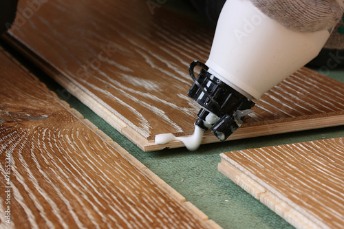 Applying glue to the ends of the parquet before laying it on the substrate photo