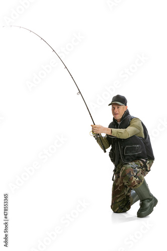 Portrait of young man, professional fisherman with fishing rod, spinning and equipment going to river isolated over white studio background