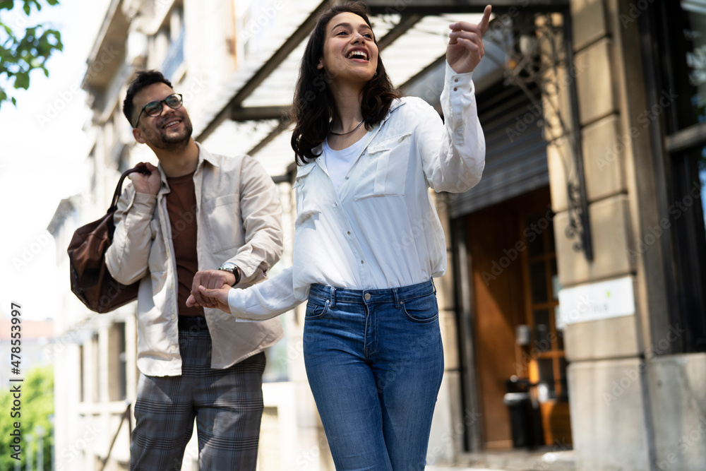 Husband and wife outdoors. Girlfriend and boyfriend walking in the city. Couple enjoy in sunny day.