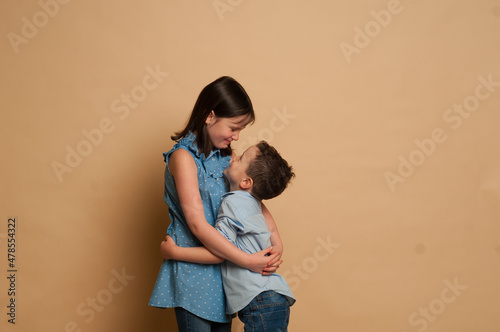 Cute little boy and girl hugging on white background