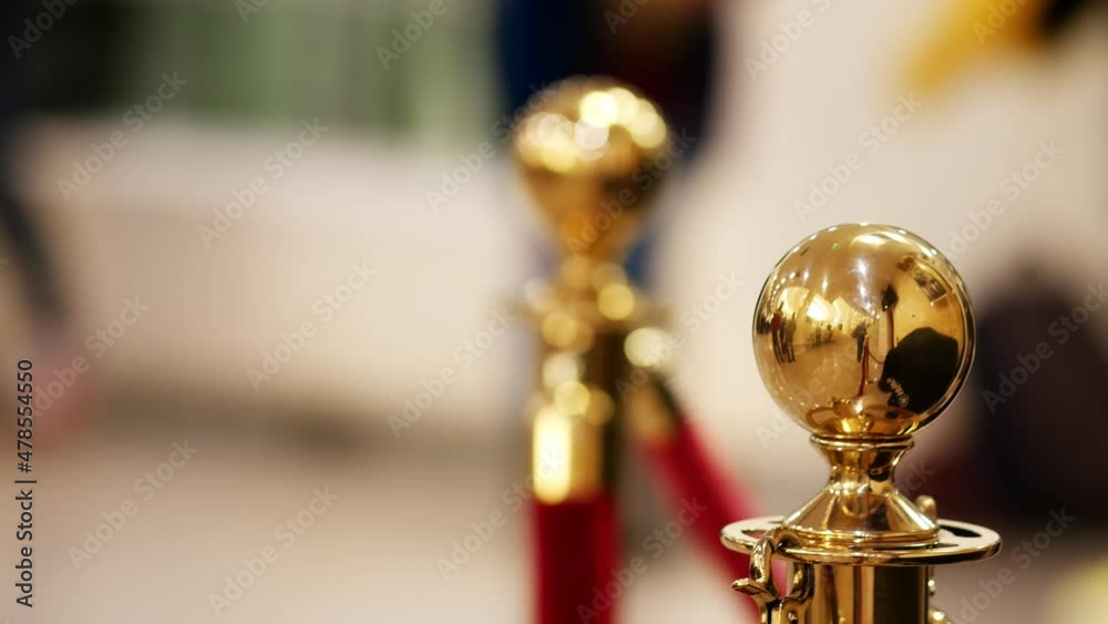 Velvet red luxury ropes closed at valuable exhibit in museum or vip zone concert or performance. Gold plated racks with polished balls. Interior barrier for presentation, show, exhibition or display Velvet red luxury ropes closed at valuable exhibit in museum or vip zone concert or performance. Gold plated racks with polished balls. Interior barrier for presentation, show, exhibition or display