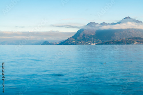 The calm waters of Lake Maggiore, Italy. Italian alps mountains with white clouds on the background.