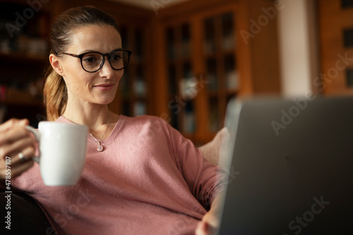 Woman working on laptop from home. Beautiful woman enjoy in fresh coffee at home.