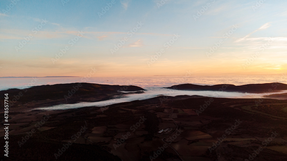 Aerial view of a sea of ​​clouds between the mountains during sunset
