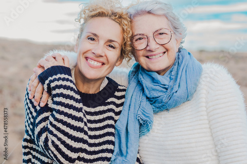 Quadro su tela Portrait of two smiling women, senior mother and mature daughter hugging with lo