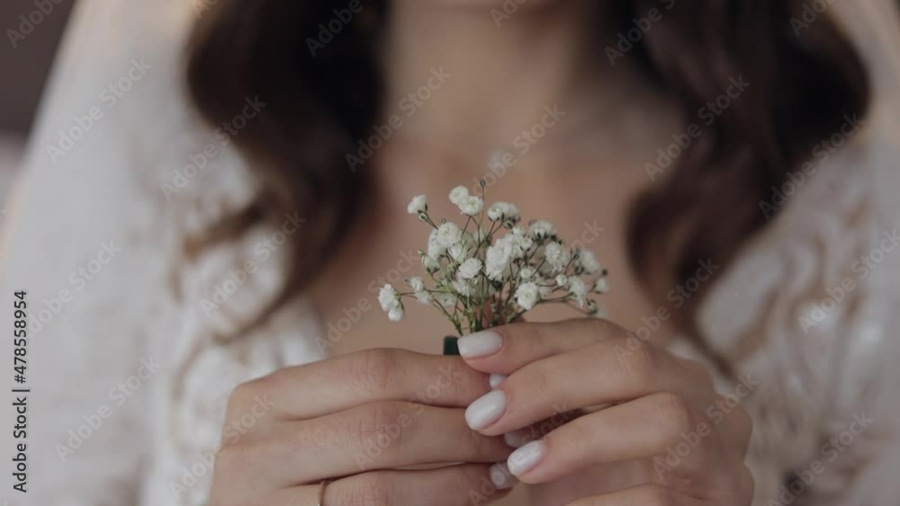 Close-up of beautiful lovely stylish bride girl holding gypsophila flowers bouquet indoors at home. Wedding morning preparations before ceremony. Bride woman face with fashion hairstyle. Slow motion Close-up of beautiful lovely stylish bride girl holding gypsophila flowers bouquet indoors at home. Wedding morning preparations before ceremony. Bride woman face with fashion hairstyle. Slow motion