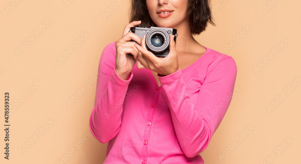 Obraz premium Woman photographer crop view holding photo camera in hands beige background, photographing