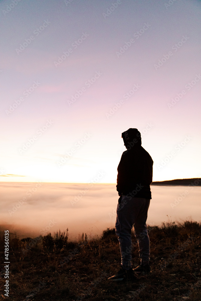 Silhouette of a boy from behind contemplating a sunset Silhouette of a boy from behind contemplating a sunset