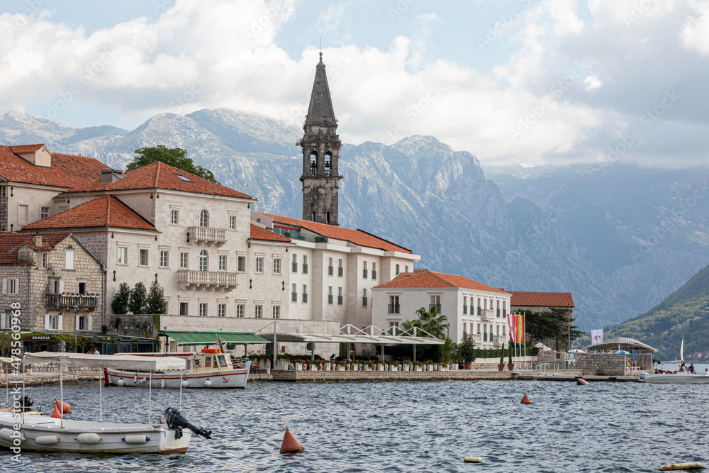 Kotor bay (Boka Kotorska) landscape, Montenegro, Europe, ancient historical town with with boats in sea water and medieval tower at background of mountains in clouds. Perast, Montenegro