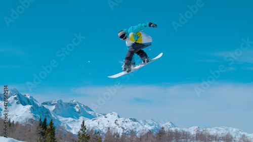 Snowboarding pro doing a rotating grab stunt while riding in Vogel.