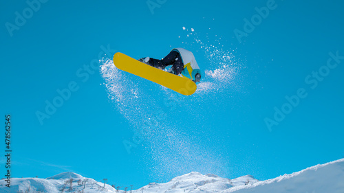 Vászonkép BOTTOM UP: Athletic male tourist snowboarding in Alps does a spinning trick